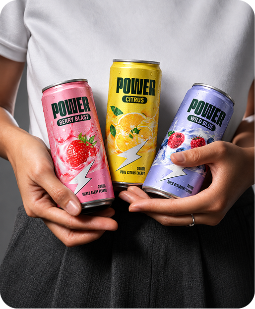 Three slim aluminum cans of POWER energy drink are held in two hands against a person's torso. The left can is pink with a strawberry graphic and the label reads 'POWER BERRY BLAST'; the center can is yellow with an orange slice graphic and reads 'POWER CITRUS'; the right can is lavender with a berry graphic and reads 'POWER WILD BLUE'.